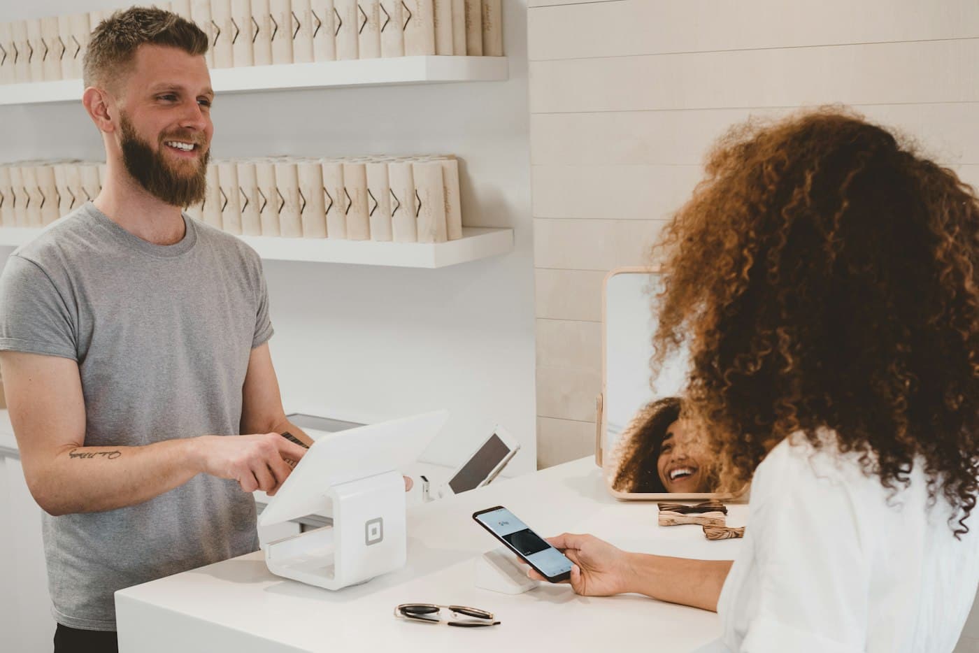 Vendeur et cliente au comptoir d’une boutique lumineuse